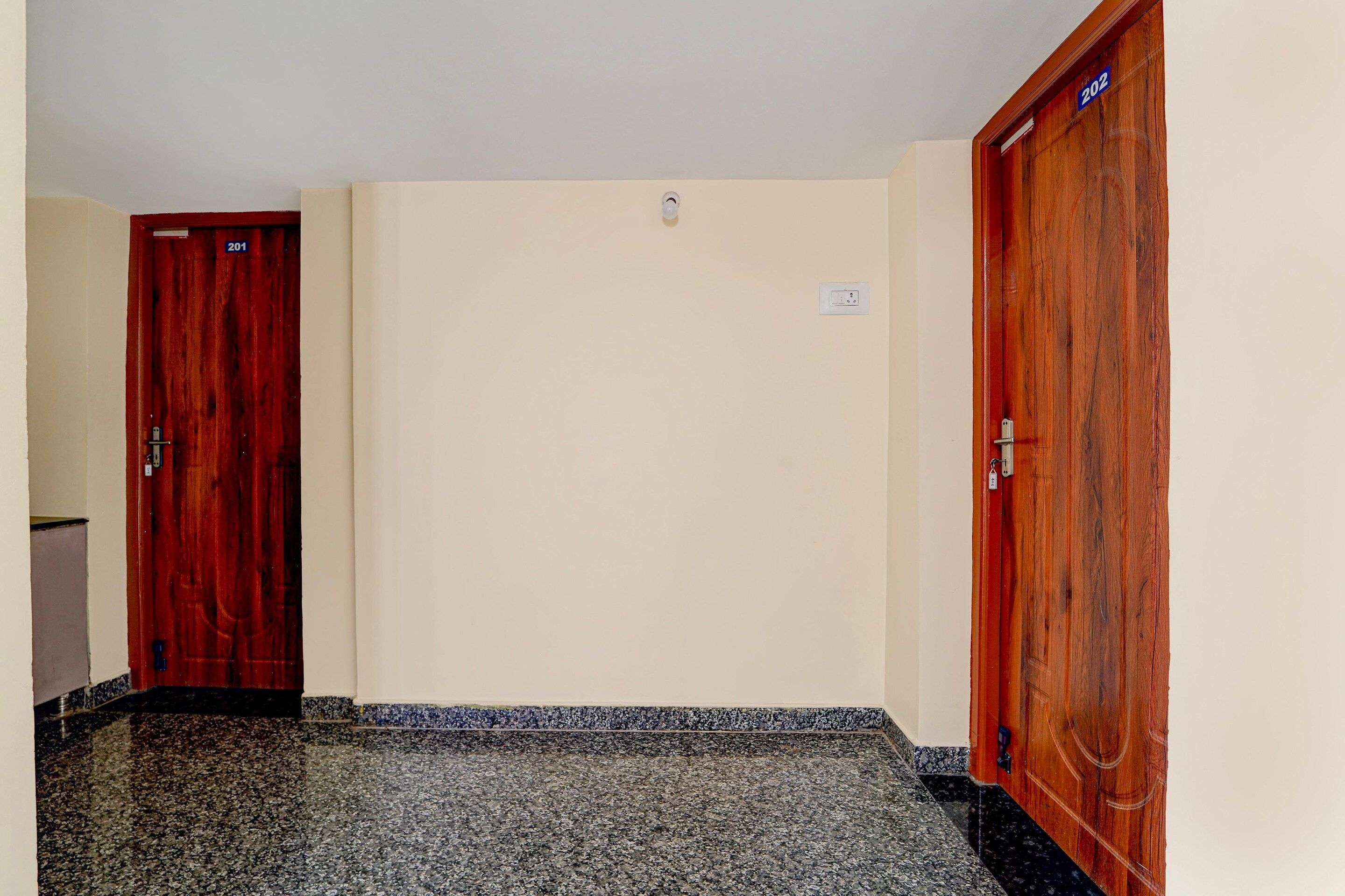 Un couloir avec deux portes en bois, numérotées 201 et 202, et un interrupteur sur le mur.