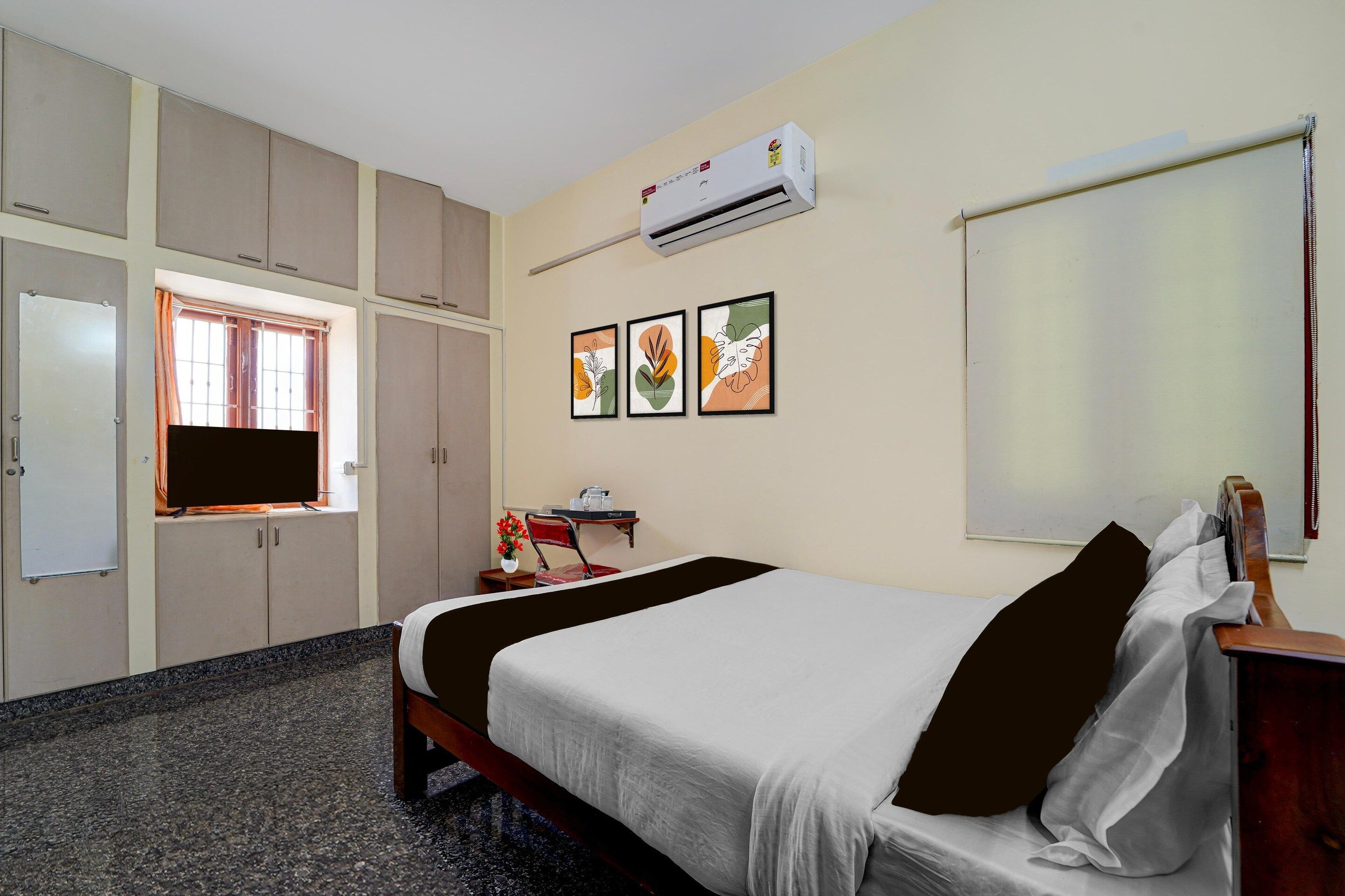 A hotel room with a bed, a desk, a chair, a TV, and a wardrobe.