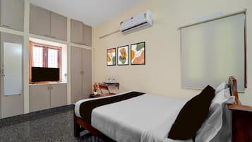 A hotel room with a bed, a desk, a chair, a TV, and a wardrobe.