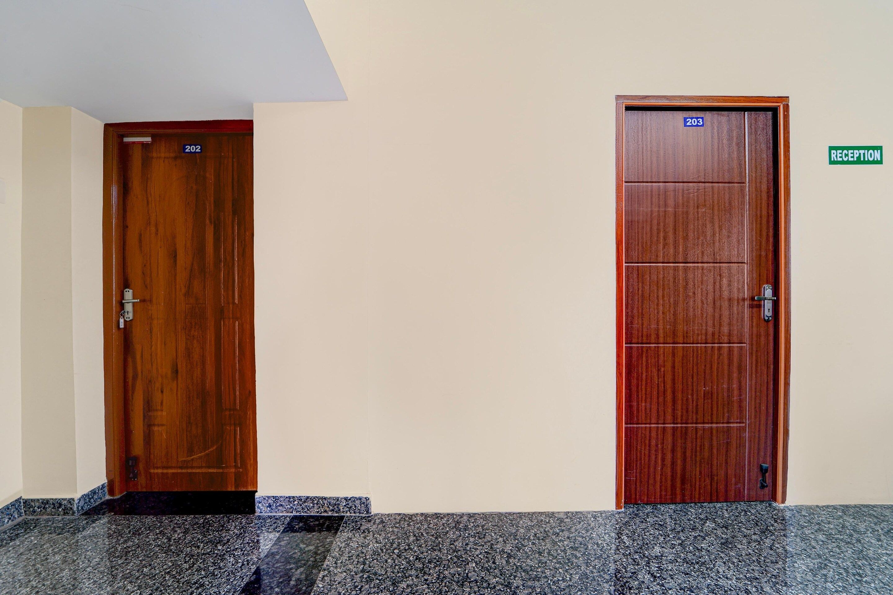 Twee houten deuren met de nummers 202 en 203, en een receptiebord aan de muur.