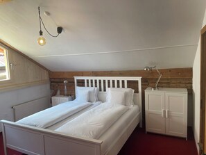 A bedroom with a bed, a nightstand, a lamp, and a wardrobe. - Plaz Aldier, (Sent) by Interhome (Sent)