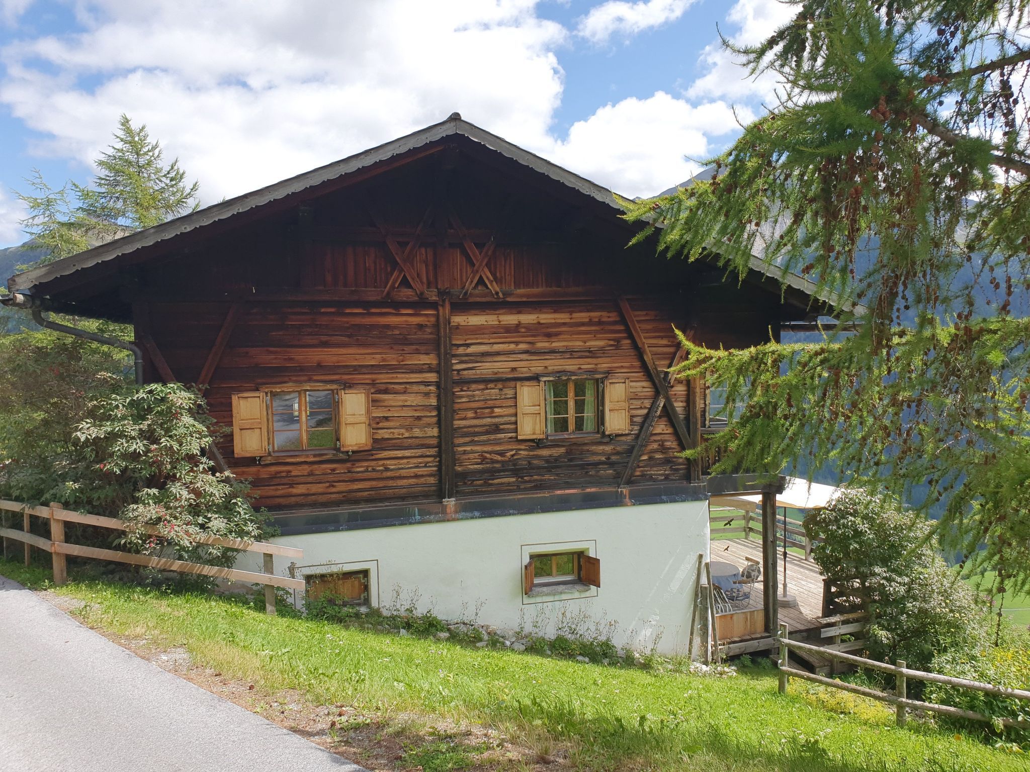 A wooden chalet with a sloped roof, a small porch, and a view of the surrounding landscape.