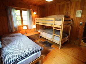 A wooden cabin room with bunk beds, a single bed, two lamps, and a window with curtains. - Ferienhaus Chas'alba, (Sta. Maria Val Müstair) by Interhome (Sta. Maria GR)