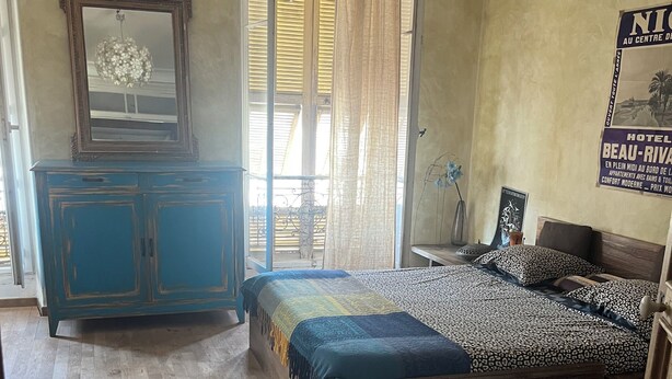 A bedroom with a bed, a dresser, a mirror, and a window with curtains.