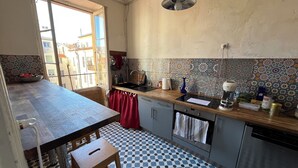 A kitchen with a checkered floor, a wooden table, a sink, and a hanging light fixture.