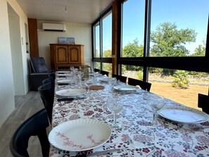 A dining table set with plates, glasses, and cutlery, with a view of trees and a clear sky.