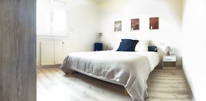A bedroom with a bed, bedside tables, a lamp, and artwork on the wall.