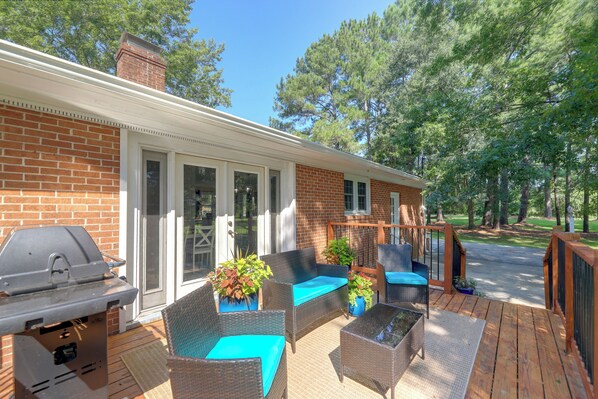 A covered patio with outdoor furniture, a grill, and a brick wall. - Back Deck, Grill, Yard! New Bern Family Home (New Bern)