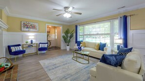A living room with a ceiling fan, a sofa, a coffee table, and a dining area with chairs. - Back Deck, Grill, Yard! New Bern Family Home (New Bern)