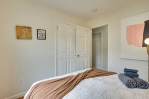 Un dormitorio con una cama, una puerta y dos cuadros en la pared.