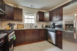 A modern kitchen with dark wooden cabinets, a stainless steel refrigerator, a built-in oven, and a microwave. - Easy NYC Commute: Furnished Jersey City Home (Jersey City)
