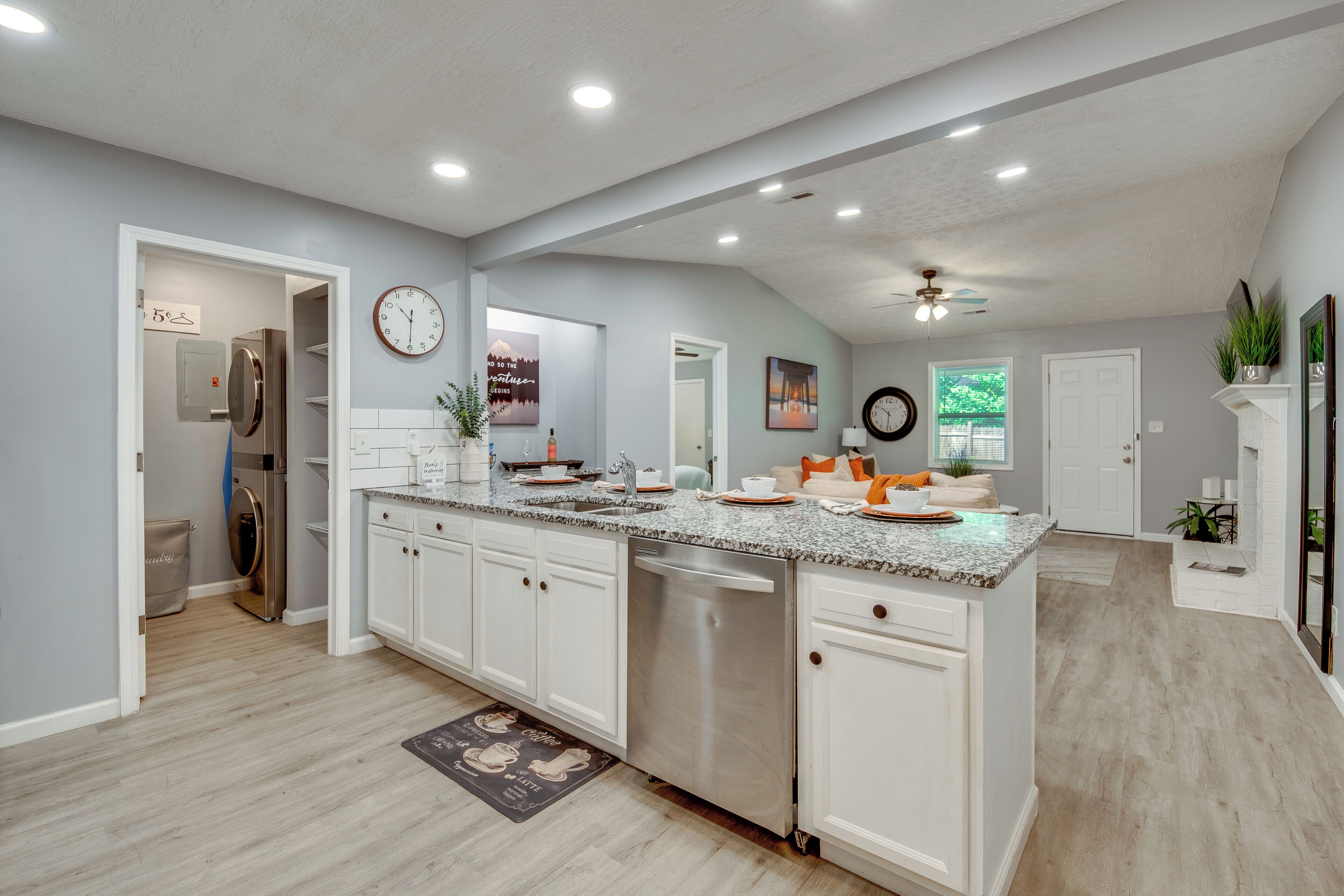 A spacious kitchen with a central island, built-in appliances, and a large clock on the wall.