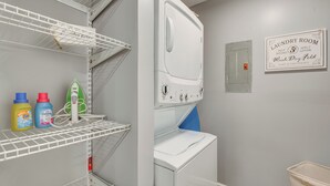 A laundry room with a white washing machine, shelves with detergent bottles, and a sign indicating laundry services. - Dual-Unit Group Getaway, 6 Mi to Atlanta Airport! (Atlanta)