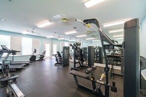 Ein Fitnessraum mit Cardiogeräten, Gewichten und Spiegeln.