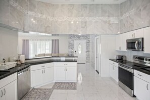 A modern kitchen with white cabinetry, a central island, and stainless steel appliances. - 3BR 2BA Pool Home Near Disney and FL Attractions (Davenport)