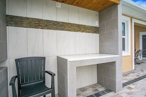 Een terras met een zwarte stoel, een witte tafel en een geaccentueerde stenen muur.