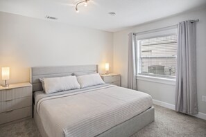 A bedroom with a bed, nightstands, a window with blinds, and a ceiling light fixture. - 3BR 2BA Pool Home Near Disney and FL Attractions (Davenport)