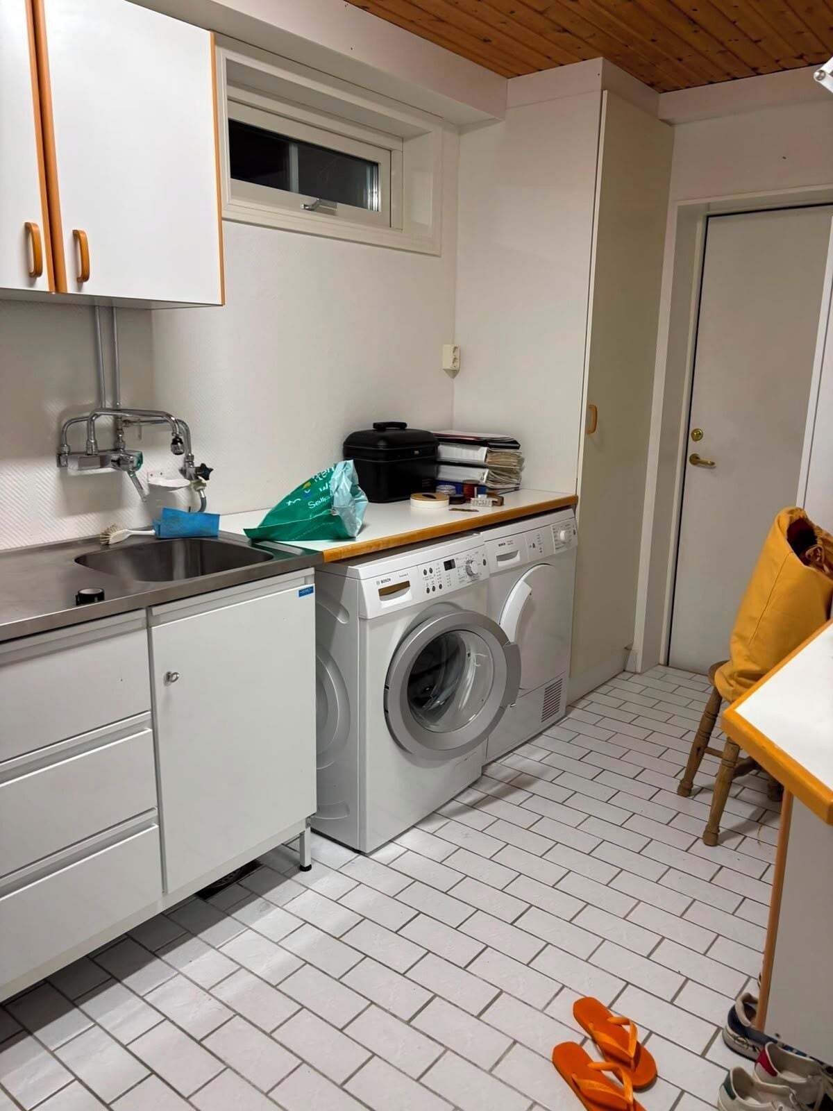 A compact laundry room with a washing machine, a sink, and a window.