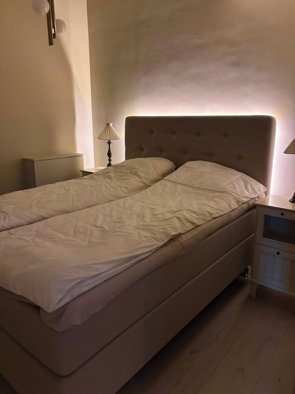 Un lit avec une tête de lit, une table de chevet et une lampe.