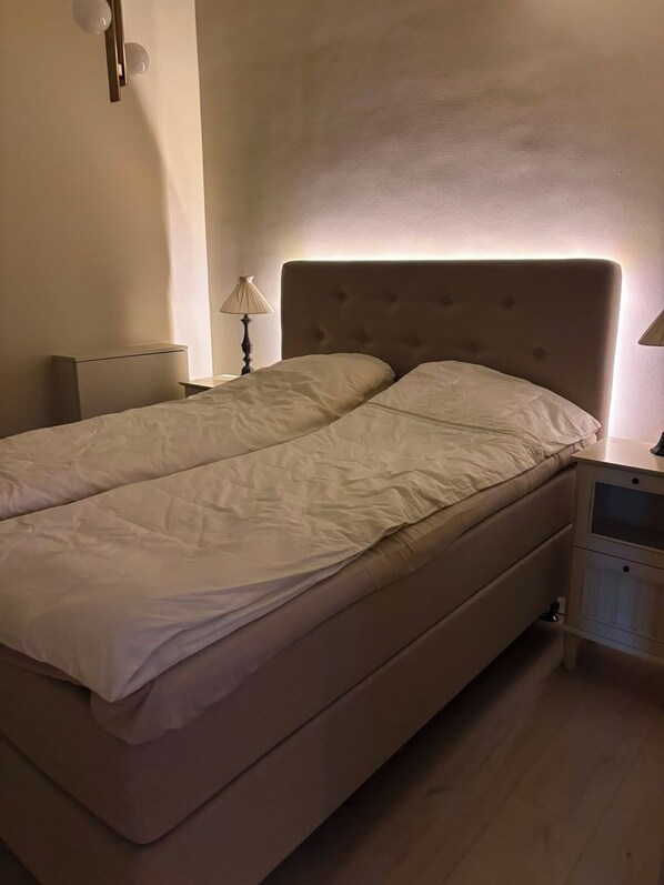 A bed with a headboard, a bedside table, and a lamp.