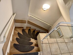 Eine Treppe mit Geländer, Holzboden und einer Wandleuchte.