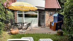 A patio area with outdoor furniture, a yellow umbrella, and a brick building with a glass door. - Süderstraße 29a, Apt. 01 - Spacious 3-room vacation apartment with a terrace and (Sylt)