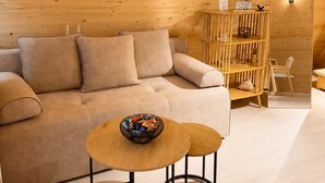 A cozy room with a wooden ceiling, a sofa, a small table with a bowl, and a wooden cabinet with a sign. - A-frame with lake view near Stepanavan (Vardablur)