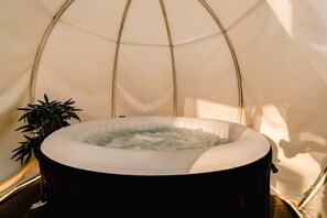 A hot tub inside a tent with a plant beside it. - Urban Deluxe Igloo Jacuzzi Terrace (București)
