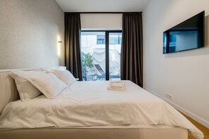 A hotel room with a bed, a TV mounted on the wall, and a view of the outside. - Urban Deluxe Igloo Jacuzzi Terrace (București)