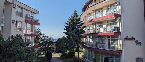 A multi-story hotel with balconies, a reception area, and a view of the sea.
