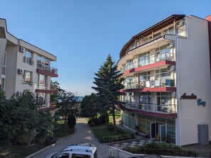 A multi-story hotel with balconies, a reception area, and a view of the sea.