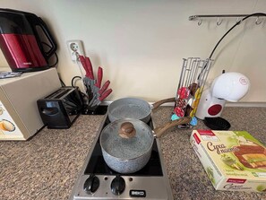 Eine Küche mit Herd, Töpfen, einer Kaffeemaschine, einem Toaster und einer Packung Gurkencreme.