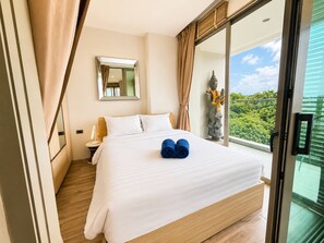 Ein Hotelzimmer mit einem großen Bett, einem Spiegel, einer Statue und Blick auf Grünflächen.