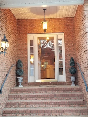 A brick building entrance with a set of stairs leading up to a door, two potted plants on either side, and a hanging light fixture above. - Right at Lake Tobesofkee & 10 miles from downtown! (Macon)
