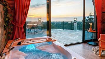 A modern bathroom with a hot tub, large windows, and a view of the cityscape.