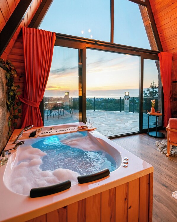 Un baño moderno con jacuzzi, ventanas amplias y vistas a la ciudad.