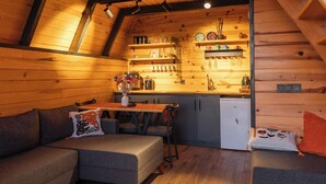 Interior acogedor de una cabaña con un altillo para dormir, kitchenette y comedor.