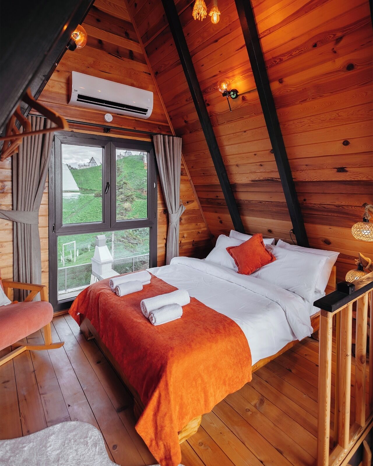 Um quarto aconchegante com uma cama, uma cadeira, uma janela e um aparelho de ar condicionado.