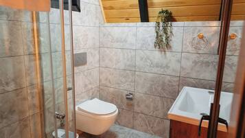 Ein Badezimmer mit einer gläsernen Duschkabine, einer Toilette und einem Waschbecken mit Holzschränken.