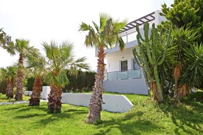 A modern building with a white facade, surrounded by palm trees and cacti. - Xenos Villa 1 With Private Swimming Pool Near The Sea (Tigkaki)