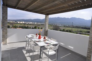 Una terraza con mesa lista para comer, con vistas a un paisaje montañoso.