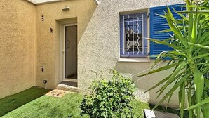 A house with a small garden, a door, and a window with blue shutters. - A charming little house near Lake Salonique. (Le Grau-du-Roi)