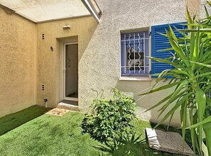 A house with a small garden, a door, and a window with blue shutters. - A charming little house near Lake Salonique. (Le Grau-du-Roi)