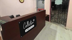 A reception desk with a sign reading 'Collection oyo-serviced' in a room with a tiled floor and a door leading outside.
