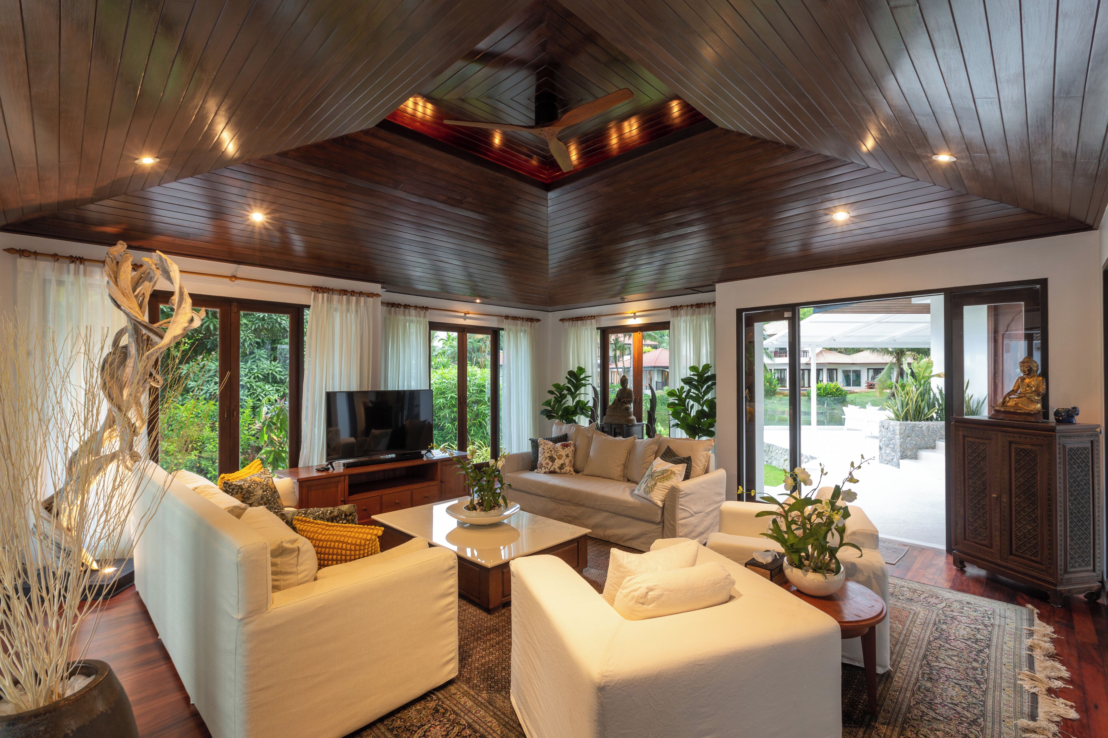 A spacious living room with a television, sofas, and a large window offering a view of the outdoors.