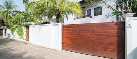 Una calle residencial con un muro blanco y una puerta de madera.