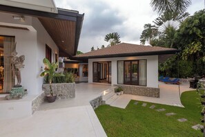 A modern house with a patio, a statue, and a well-maintained garden. - Surin Lake Villa (Thalang District)