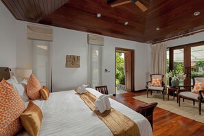 A hotel room with a bed, a chair, a table, and a view of the outdoors. - Surin Lake Villa (Thalang District)