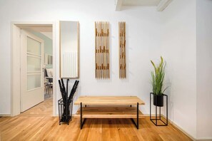 A modern interior with a wooden bench, a potted plant, and a wall-mounted mirror. - Large Central Apt | Game Room • Xbox Pass • Fun (Praha 2)