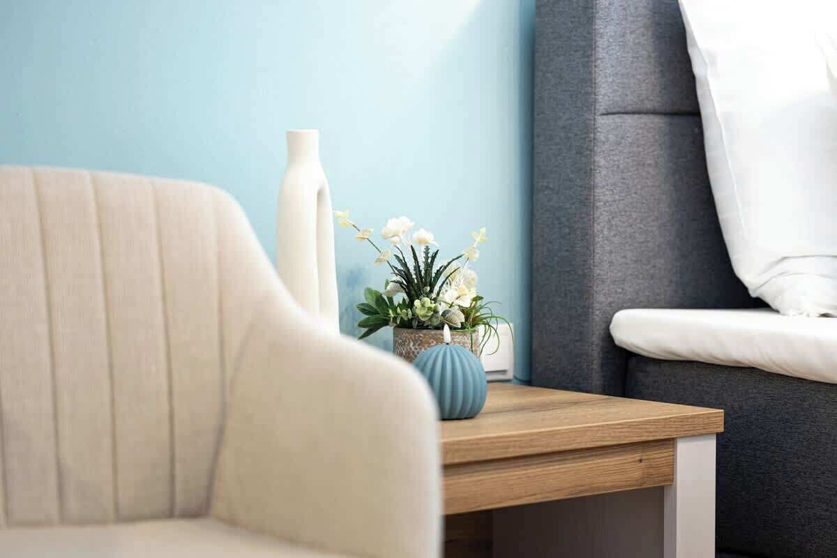 Un canapé, une table d’appoint en bois et un vase avec des fleurs.
